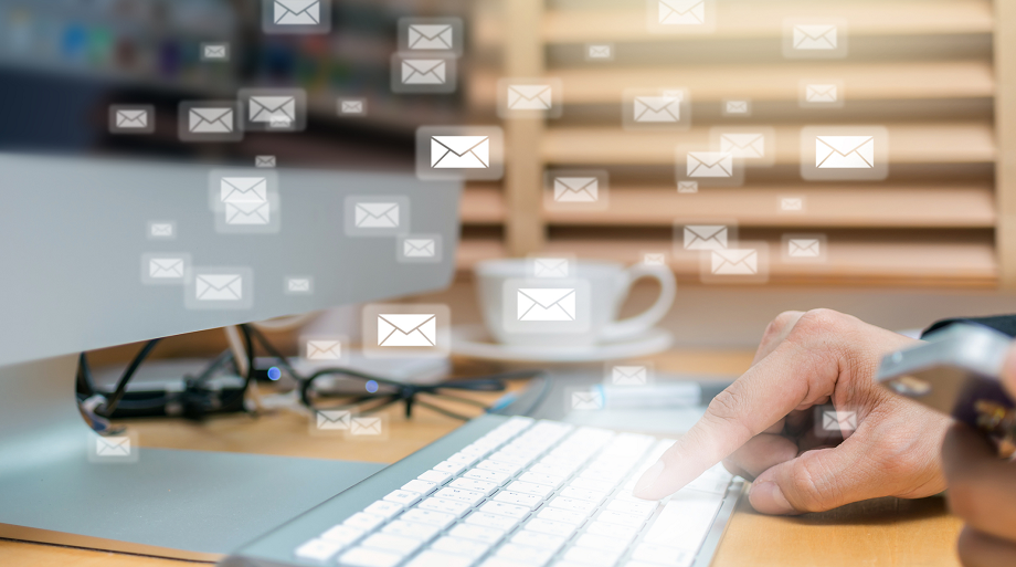 A person's hand typing on a keyboard with envelope symbols floating over the image.